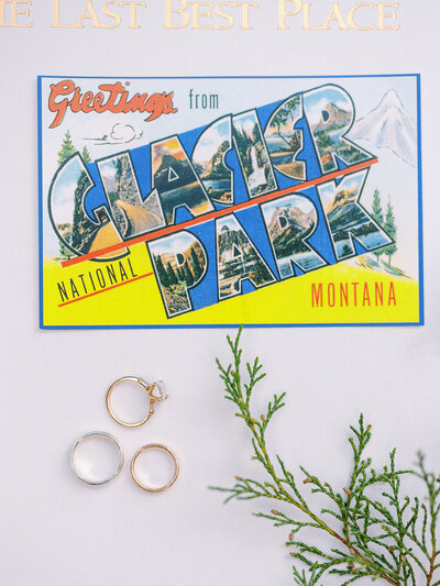 Detail photo of wedding rings styled with a Glacier National Park postcard in the background.