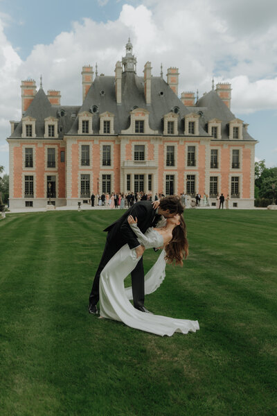 bride and groom dip kiss in front of Chateau in France
