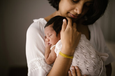 A mother holding her newborn babe during a newborn lifestyle photoshoot with studio photographer aimee kelly photography