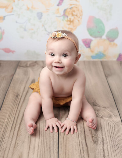 Baby girl sitting and smiling in our Rochester, NY studio.