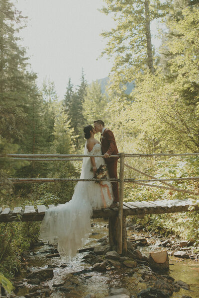 groom kissing his bride on a bridge
