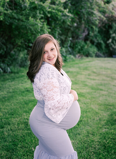 A smiling pregnant mom in a green park. Photo by Diane Owen Photography.