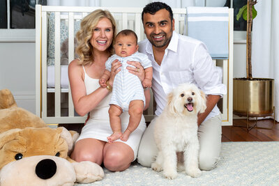 Family photo in a baby nursery with small white dog