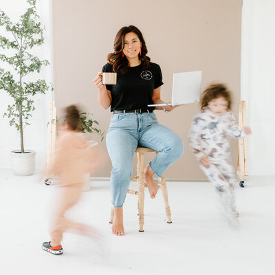 Yvonne (New England Event Planner) from Unique Melody Events & Design sitting on stool with kids running around her