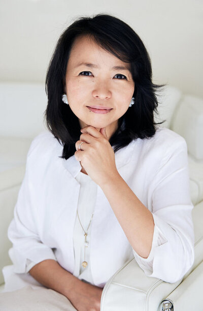 Headshot of Momoya, dressed in white on a white sofa