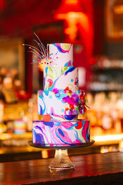 A four tiered cake with colorful swirls on it.