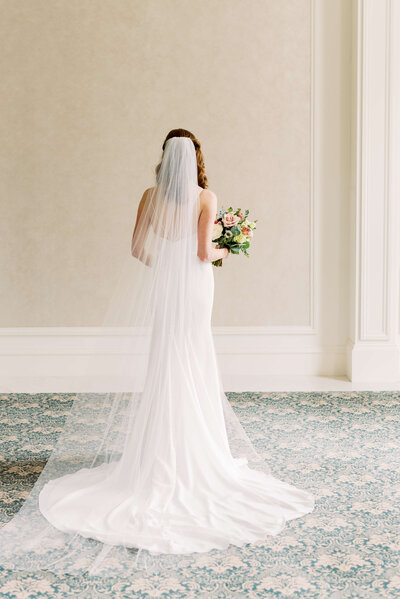 Bride with her back to the camera with long veil spread out