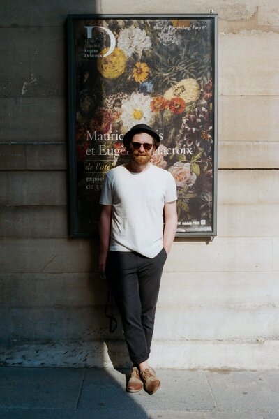 35mm film photo of editorial wedding photographer Tomasz Wagner standing in front of a poster in Paris