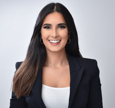 Young professional woman  looking at camera smiling against white backdrop