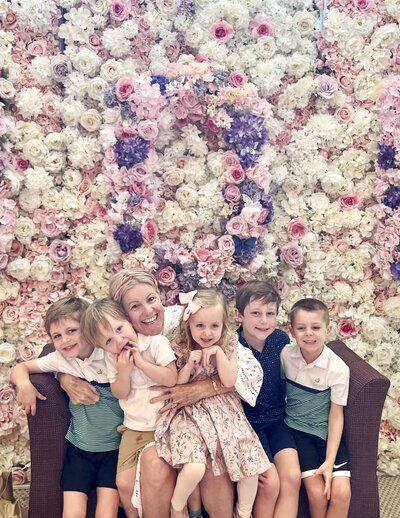 grandmother with her grandchildren sitting in front of a wall of flowers