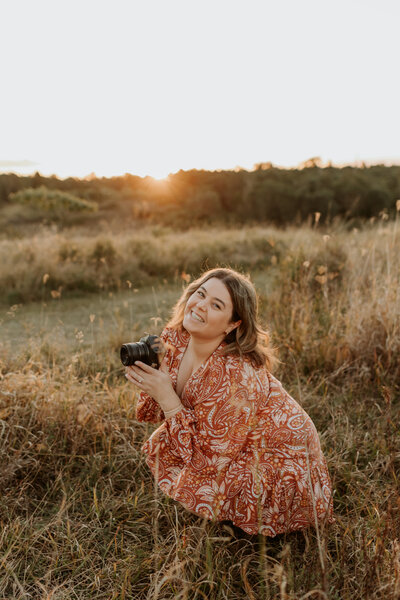 girl holding camera in a long grassy field