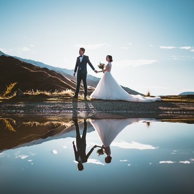 Bride and groom reflected in a pond