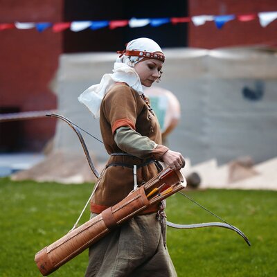 medieval-archery-tournament-a-woman-shoots-an-arrow-in-the-medieval-castle-yard-woman-in-medieval-dress-with-a-wooden-bow-in-her-hands-historical-reconstruction-14052022-yoshkar-ola-russia