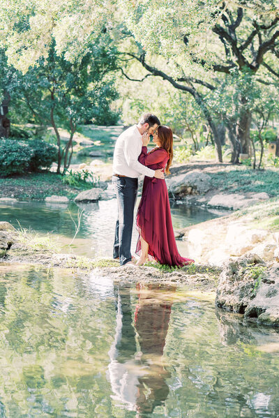 San Antonio engaged couple kisses by the water underneath beautiful oak trees