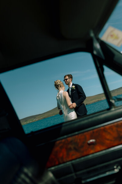 bride and groom kissing at the waters edge