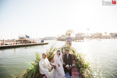 Bride and Groom sit together next to the officiant as they take a arid on a gondola in Long Beach