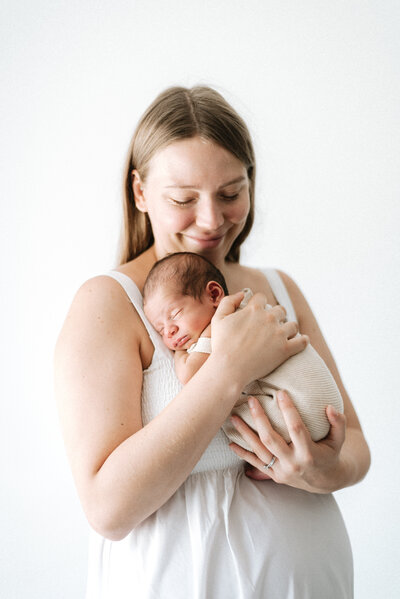 Newborn in mums arms during a natural newborn photoshoot in Billingshurst
