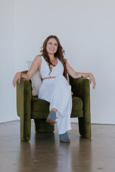 female-entreprenuer-in-white-suit-seated-in-green-chair-for-mini-brand-session-portrait-the-frame-charlotte
