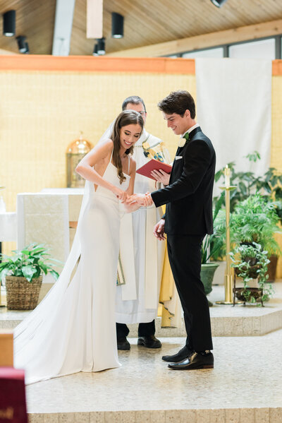 Bride putting the ring on the groom's finger during Catholic wedding ceremony