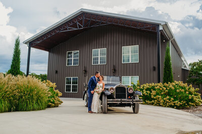 photo of bride and groom leaning on a vintage car