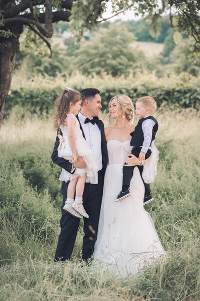 bride and groom holding kids