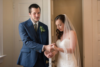 bride and groom hold hands in prayer at womans club of portsmouth in virginia