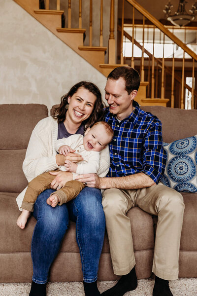 Mom and dad playing with their son and tickling him on the couch by Milwaukee Family Photographer Ashley Kalbus.