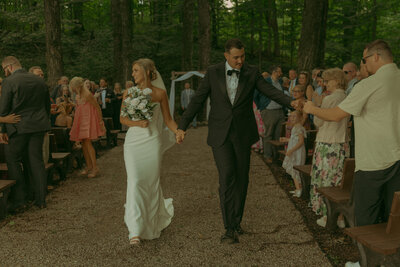 Newlyweds hold hands and run out of the church together, surrounded by streamers and loved ones