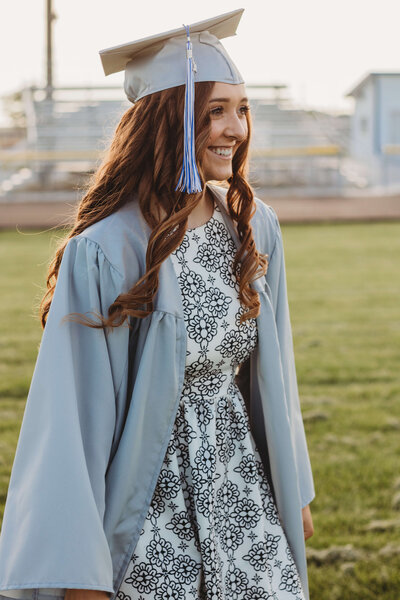 Senior walking across the football field while wearing her cap nad gown