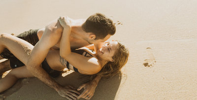 man and woman laying on sand