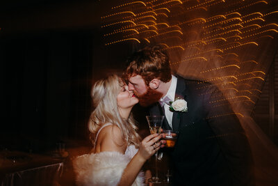 bride and groom kissing holding drinks