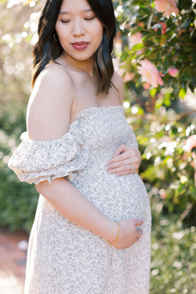 mother holds pregnant belly with spring flower dress