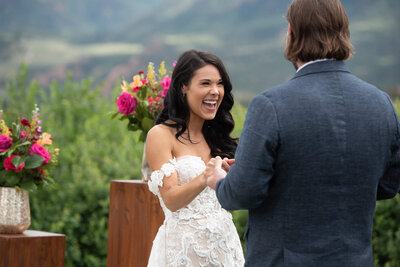 Bride smiling big while her groom shares his vows during their ceremony on the lawn at Garden Of The Gods Club in Colorado Springs