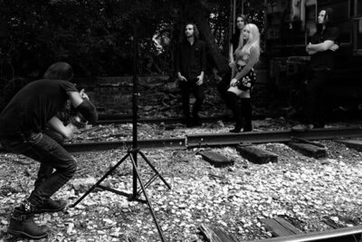 Behind the scenes Nashville Tennesse photoshoot Mark Maryanovich photographing Juliana Hale And Band of Roses standing against trailer and trees black and white image