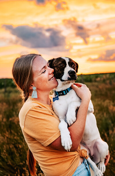 Woman holding pitbull dog snuggling in open field