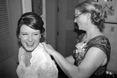 bride and mother of the bride zipping up brides dress smiling black and white picture by las vegas wedding photographers mkdelacy