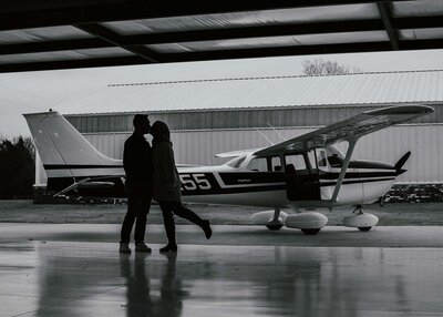Maddie rae Photographyvcouples silhouette of them kissing with her leg up and there is an airplane in the background