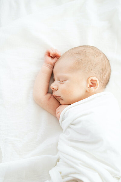 newborn baby swaddled in white