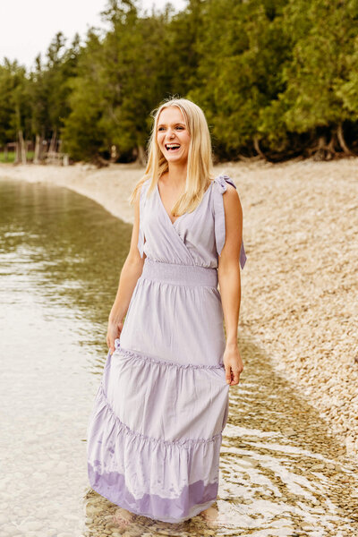 beautiful senior girl walking in the water and laughing during her session in door county
