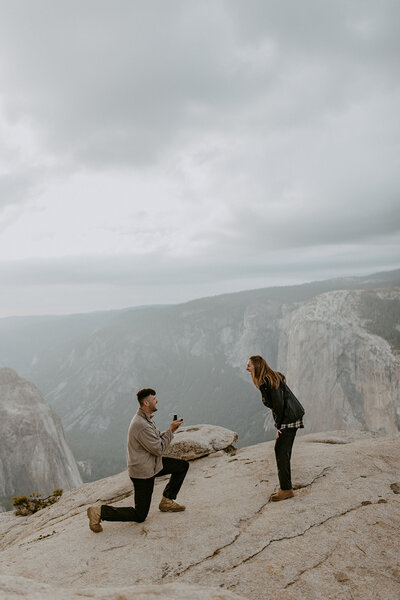man is down on one knee proposing in yosemite national park