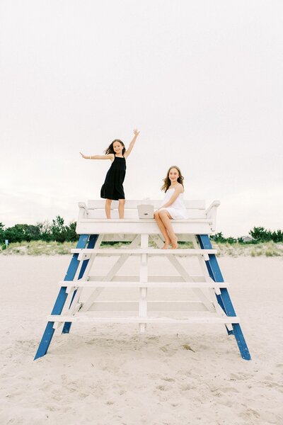 Young sisters posing on lifeguard stand on the beach
