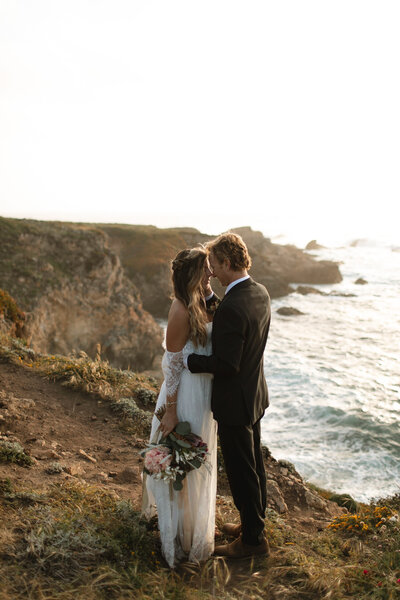 A bride and a groom enjoying a moment together at sunset. The bride is holding her flowers by her side with her right hand.