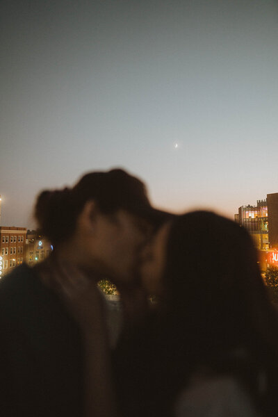 jackie and michael, wedding photographers kiss beneath the light of the crescent moon with downtown boise in the background