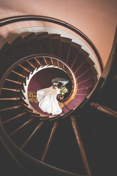 Bride and Groom kissing at the bottom of spiral staircase after wedding in Madison, Indiana