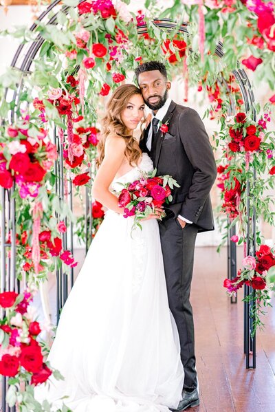 Bride and groom standing in front of floral arch