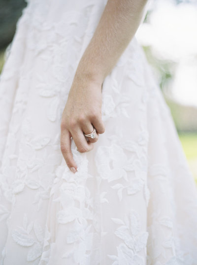 Detail wedding shot of bride holding dress with rose gold ring