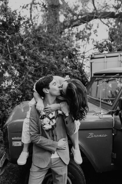 woman kissing a man while sitting on a car