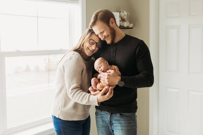 A serene moment during a Harrisburg lifestyle newborn  Session as a newborn sleeps peacefully on a parent's chest, surrounded by loving hands.