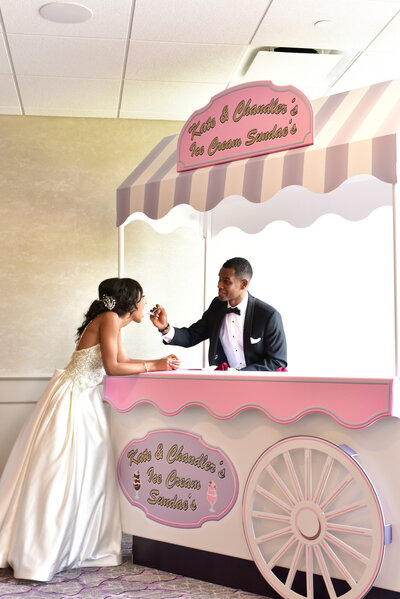 Groom feeding her wife while standing beside the dessert cart