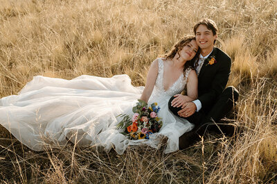 bride and groom snuggle in a field at sunset
